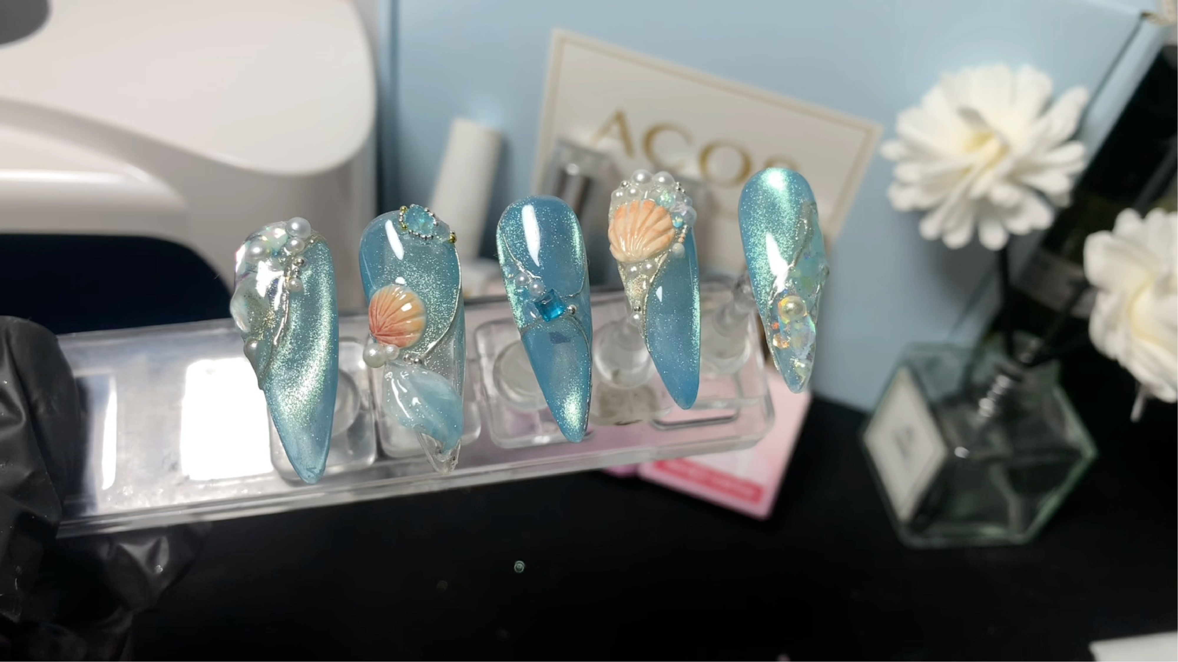 Fresh ocean inspired cat eye look with luminous blue shimmer, shell accents, pearls and crystal detailing.